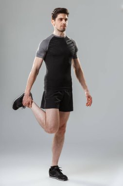 Gri arka plan üzerinde izole ısınma odaklı bir genç sporcu tam uzunlukta portresi