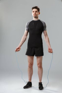 Gri arka plan üzerinde izole bir atlama ip ile yoğun bir genç sporcu tam uzunlukta portresi