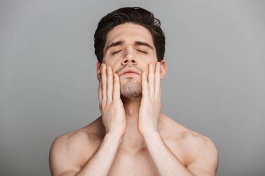 Yarı çıplak yakışıklı genç adam gri arka plan üzerinde izole yüzünü dokunaklı Güzellik Portresi