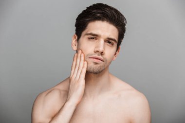 Yarı çıplak yakışıklı genç adam gri arka plan üzerinde izole yüzünü dokunaklı Güzellik Portresi