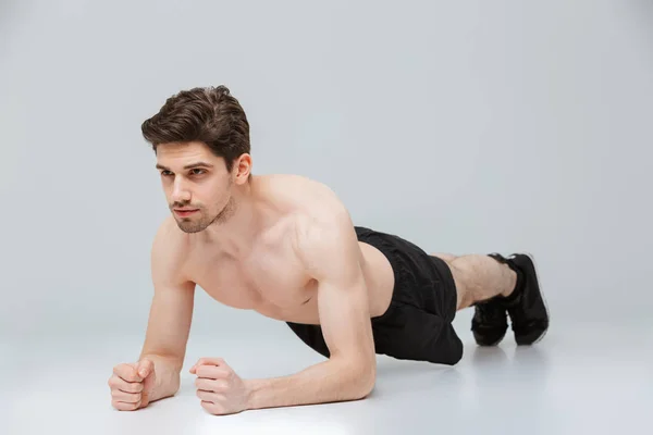 Retrato Joven Deportista Semidesnudo Concentrado Haciendo Ejercicios Tablón Sobre Fondo — Foto de Stock