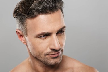 Yakışıklı ciddi olgun adam çıplak gri duvar arka plan üzerinde izole ayakta resmi. Bir kenara arıyorsunuz.