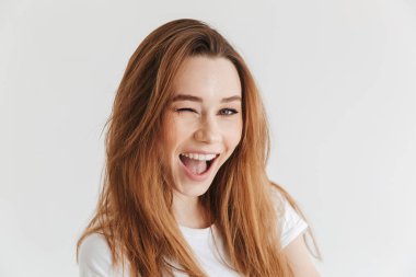 Mutlu kadın t-shirt winks onu göz ve kameraya bakmaktan gri arka plan