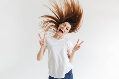 Barış hareketleri gösterilen ve gri arka plan üzerinde kameraya bakarak t-shirt neşeli kadın