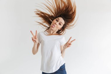 Komik kadın t-shirt gösteren barış hareketleri ve gri arka plan üzerinde kameraya ararken dilini