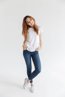 Tam boy görüntü gülen kadının kollarında cepler ile poz ve gri arka plan üzerinde kameraya bakarak t-shirt