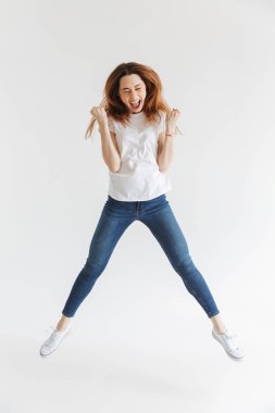 Tam t-shirt atlama içinde mutlu kadın görüntüsünü uzunluğu ve gri arka plan üzerinde sevinir