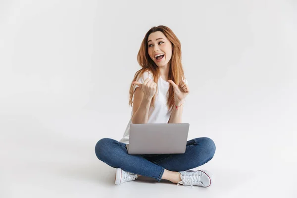 Mujer Agradable Camiseta Sentada Suelo Con Computadora Portátil Mientras Señala —  Fotos de Stock