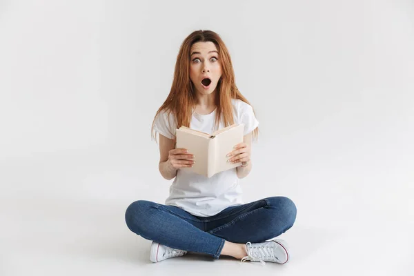 Geschokt Vrouw Shirt Zittend Vloer Terwijl Het Boek Houden Kijken — Stockfoto