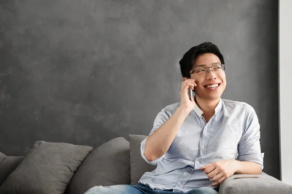 집에서 소파에 앉아있는 전화에 얘기는 아시아 남자의 초상화 — 스톡 사진