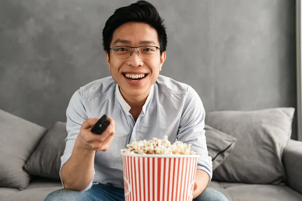 Porträtt Lycklig Ung Asiatisk Man Hålla Popcorn Och Fjärrkontrollen Medan — Stockfoto
