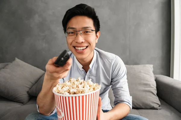 Porträtt Glad Ung Asiatisk Man Hålla Popcorn Och Fjärrkontrollen Medan — Stockfoto