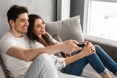 Mutlu bir adam ve kadın evde kanepede oturan ve elinde uzaktan kumanda ile televizyon izlerken görüntü