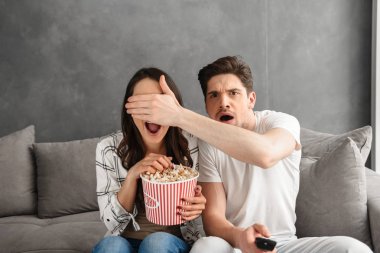 Kanepe evde patlamış mısır ile el korku filmi izlerken oturup beyaz sinirli aile görüntüsü