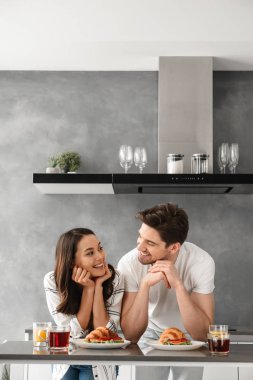 Portait birbirine bakarak ve evde kahvaltı sırasında başkanları eliyle yaslanır süre gülümseyen mutlu çift