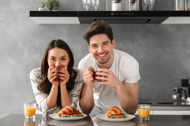 Sana bakmak ve başkanları eliyle yaslanır ve evde kahvaltı ederken gülümseyen çift