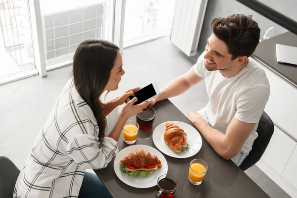 Zdjęcie Góry Wesoły Mężczyzna Kobieta Kolacji Domu Kuchni Smartphone Ręku — Zdjęcie stockowe