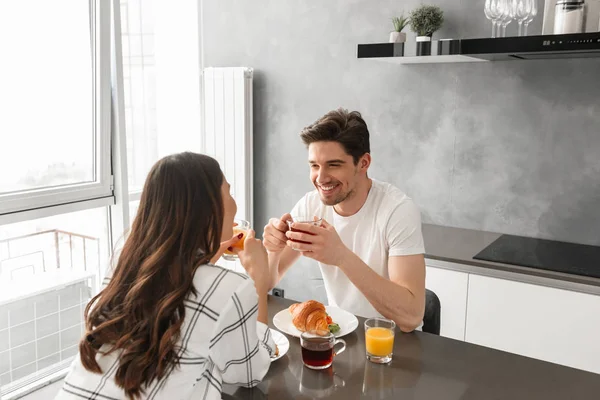 Portait Pleased Couple Looking Each Other Smiling While Sitting Kitchen — Stock Photo, Image