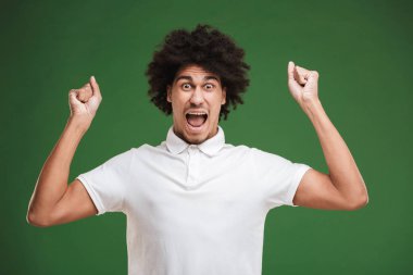 Yeşil duvar arka plan üzerinde izole mutlu Afrika kıvırcık delikanlı fotoğraf olun kazanan jest.