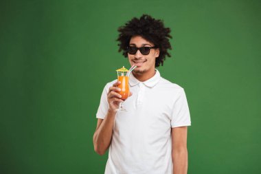 Yeşil duvar arka plan kokteyl içme üzerinde izole mutlu Afrika kıvırcık delikanlı imajını.