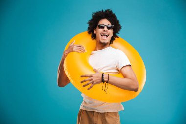 Kauçuk halka tutarak kamera arıyorum mavi arka plan üzerinde izole mutlu yakışıklı genç Afrika kıvırcık adam ayakta fotoğrafı.