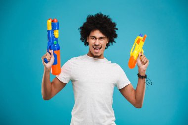 İki su üzerinde mavi arka plan izole silah tutan bir heyecanlı genç Afrika adam portresi