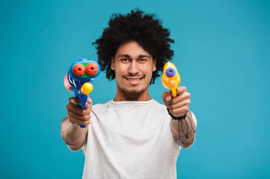 İkişer su üzerinde mavi arka plan izole top oynarken gülümseyen genç Afrika adam portresi