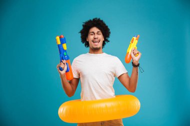 Having oyunculuk ile iki su silahlar ve mavi arka plan üzerinde izole şişme çalmak gülen genç Afrika adam portresi