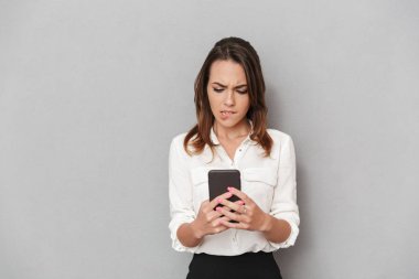 Cep telefonuyla beyaz arka plan üzerinde izole bir hayal kırıklığına uğramış genç iş kadını portresi