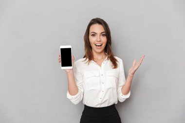 Boş ekran cep telefonu izole beyaz arka plan üzerinde gösterilen bir heyecanlı genç iş kadını portresi