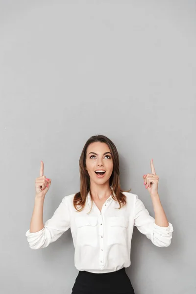 分離灰色の壁背景見て脇のポイントに立って興奮して陽気な若いビジネス女性のイメージ — ストック写真