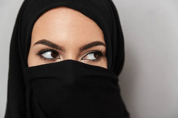 关闭的肖像一个美丽的阿拉伯妇女戴头巾看着远离灰色背景隔离 — 图库照片