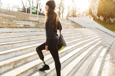 Kız merdivenlerden sokakta yürürken spor giyim Protez bacak ile çalışan devre dışı görüntü