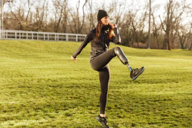 Mutlu Engelli 20'li kadında doğa spor yapıyor ve Protez bacak yükselterek eşofman görüntüsünü