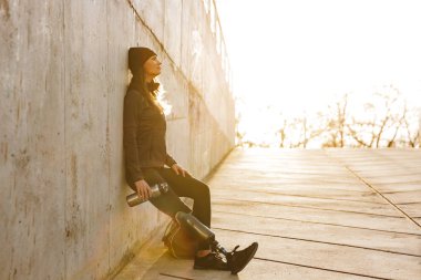 Biyonik bacak ayakta ve beton duvarı açık gülümseyen spor giyim ile atletik engelli kız fotoğrafı