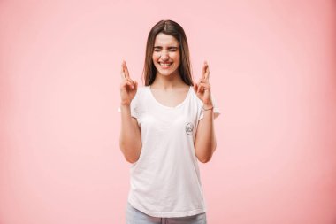 İyi şanslar pembe arka plan üzerinde izole için dua tutan bir heyecanlı genç kadın portresi