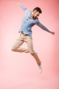Atlama ve başarı pembe arka plan izole kutlama neşeli bir genç adam tam uzunlukta