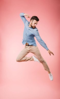 Atlama ve başarı pembe arka plan izole kutlama yakışıklı bir genç adam tam uzunlukta