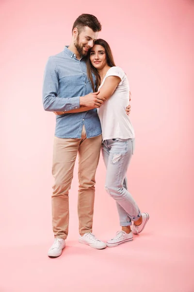一个快乐的年轻夫妇的全长肖像拥抱 而站在粉红色背景隔离 — 图库照片