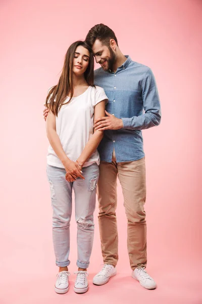 可爱的年轻夫妇的全长肖像拥抱 而站在粉红色背景隔离 — 图库照片