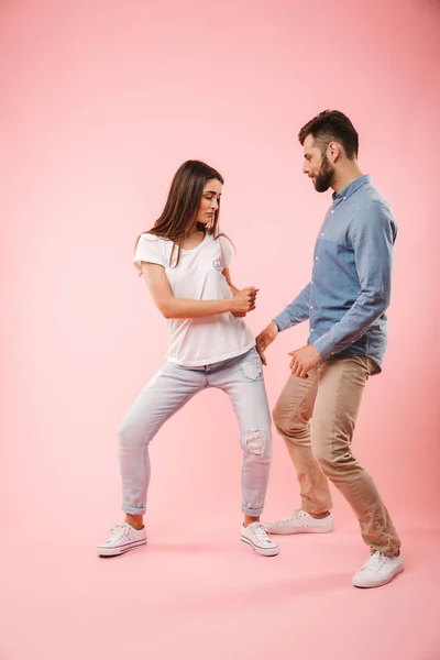 一个欢快的年轻夫妇的全长肖像一起跳舞孤立的粉红色背景 — 图库照片