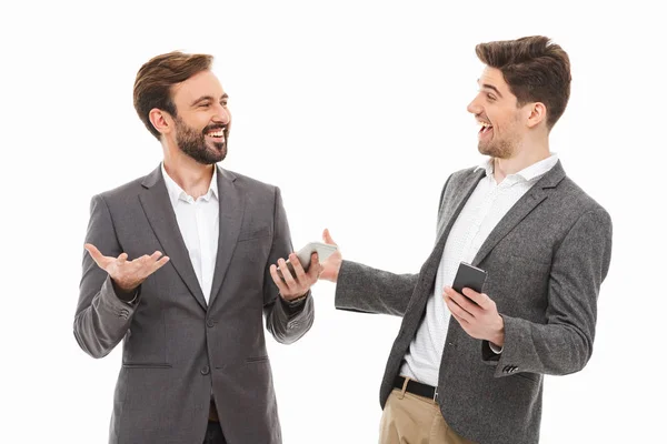 Retrato Dois Homens Negócios Satisfeitos Segurando Telefones Celulares Falando Isolado — Fotografia de Stock