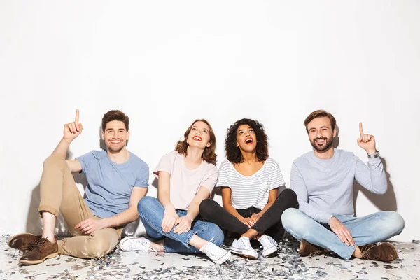 Group Happy Multiracial People Sitting Floor Confetti Pointing Isolated White — Stock Photo, Image