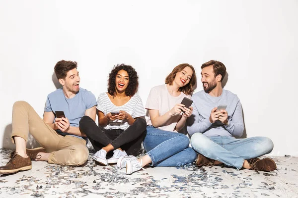 Grupo Pessoas Multirraciais Alegres Sentadas Chão Com Confete Usando Telefones — Fotografia de Stock