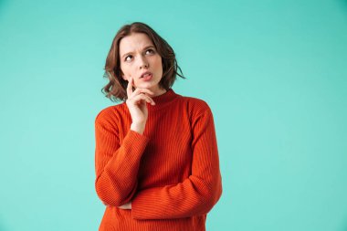 Dalgın bir genç kadının portresi üzerinde mavi arka plan izole kopya alanı uzağa bakarak kazak giymiş