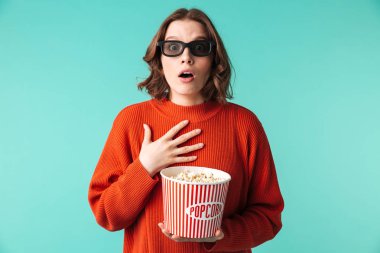 3d gözlük izole mavi arka plan üzerinde patlamış mısır yemek şok bir genç kadının portresi giymiş