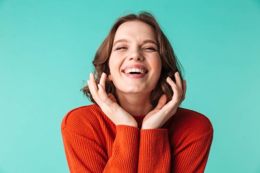 Mavi arka plan üzerinde izole kamera bakarak gülen bir genç kadın portresi