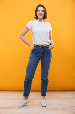 Görüntü izole kamera seyir sarı arka plan üzerinde duran mutlu genç kadın.