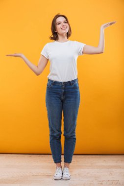Sarı arka plan üzerinde gösterilen boşaltmak izole duran neşeli genç kadın görüntüsünü.