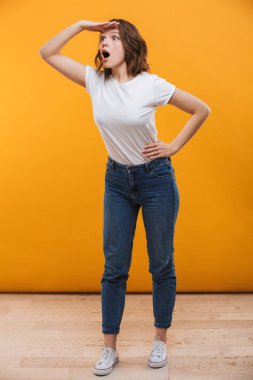 Sarı arka plan bir kenara inceliyorlar izole duran duygusal genç kadın görüntüsünü.